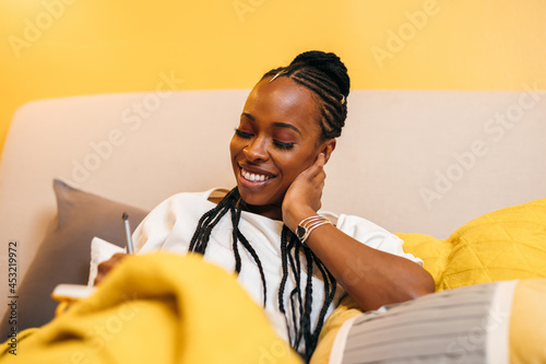 Black woman writes in journal at home in bed photo