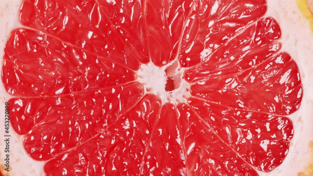 Slow motion of rotation ripe sliced grapefruit. Circle of fresh citrus as food background. Tropical fruits. Concept of proper nutrition or healthy lifestyle. Macro shot. Slow motion of rotation ripe sliced grapefruit. Circle of fresh citrus as food background. Tropical fruits. Concept of proper nutrition or healthy lifestyle. Macro shot.