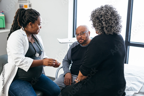 African American female doctor consults with senior medical patients about prescription drugs