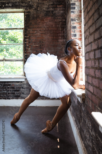 Black ballerina doing powerful ballet dance pose, wearing pointe shoes and white tutu photo