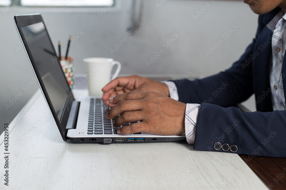 Side view of unrecognizable businessman typing on laptop. Closeup hands on the computer keyboard typing. Side view of unrecognizable businessman typing on laptop. Closeup hands on the computer keyboard typing.