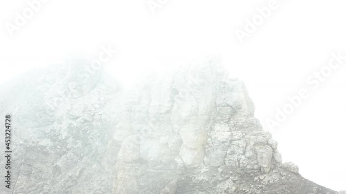 Aerial of Large rock on mountain top surrounded with thick mist photo