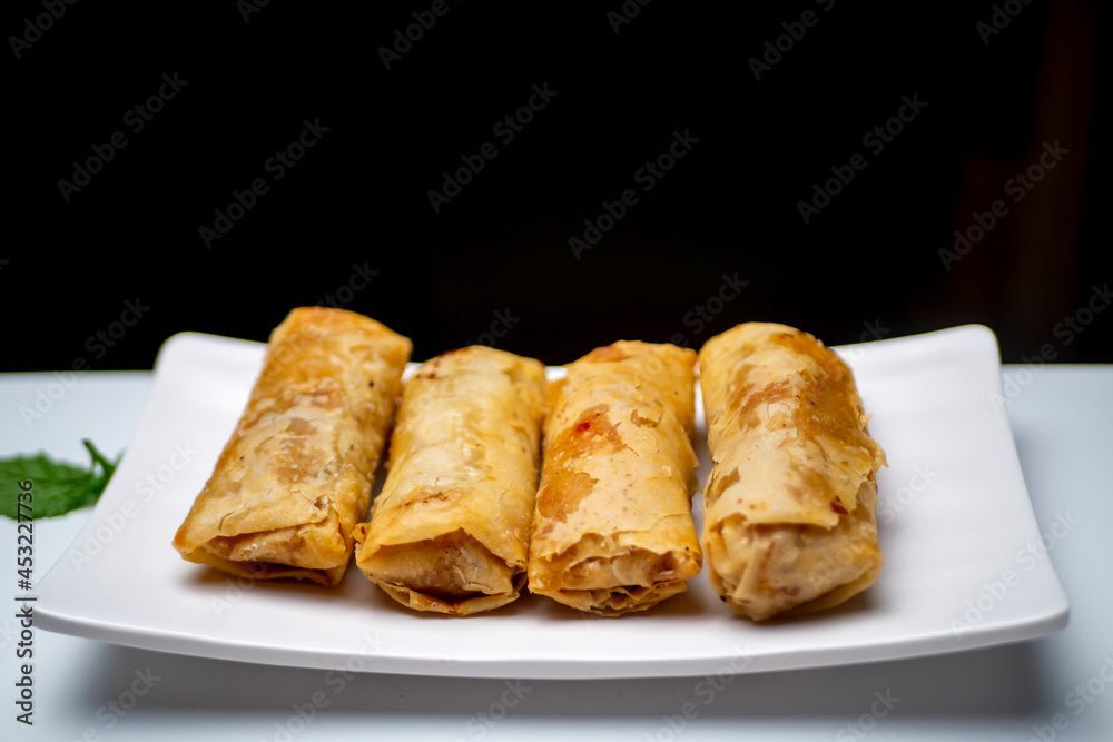 A plate of lumpia, spring rolls as Indonesian traditional food, on a white table A plate of lumpia, spring rolls as Indonesian traditional food, on a white table