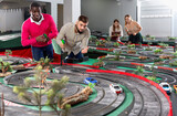 Two adult friendly men playing with childrens slot car racing track