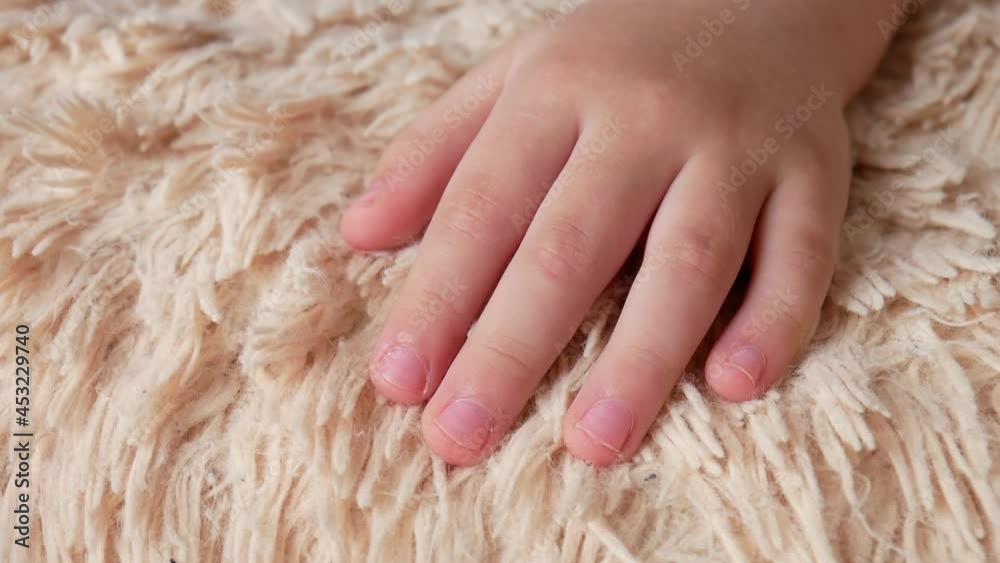 Close-up of a sleeping child's hand moving the fingers on a fleecy blanket Close-up of a sleeping child's hand moving the fingers on a fleecy blanket