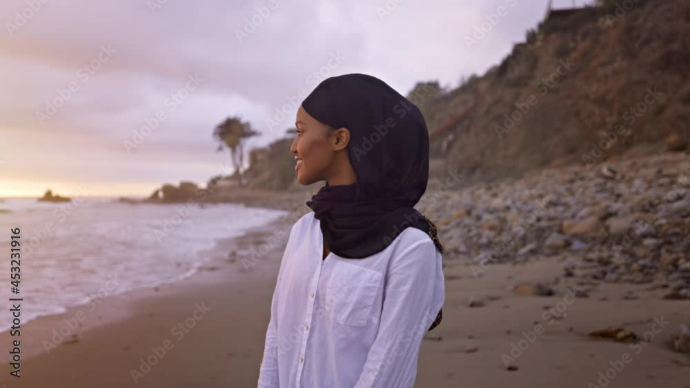Somali-American woman walking on the beach in Malibu at sunset. Somali-American woman walking on the beach in Malibu at sunset.
