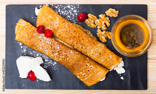 Top view of Bulgarian-style crepes Palatschinke with filling of brynza and walnuts with honey on black board photo