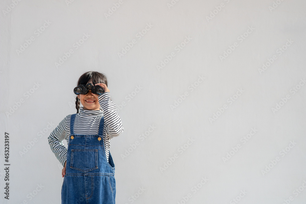 Little Asian girl looking through binoculars in white background. Explore and adventure concept. Little Asian girl looking through binoculars in white background. Explore and adventure concept.