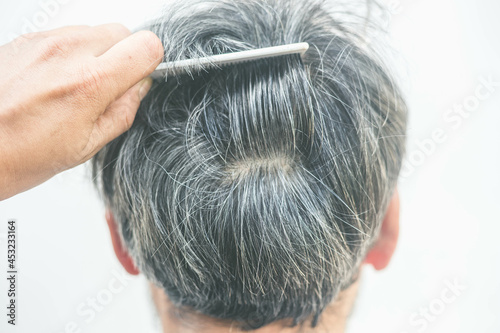 The old man opened the gray hair roots with a comb. Gray hair problem concept
