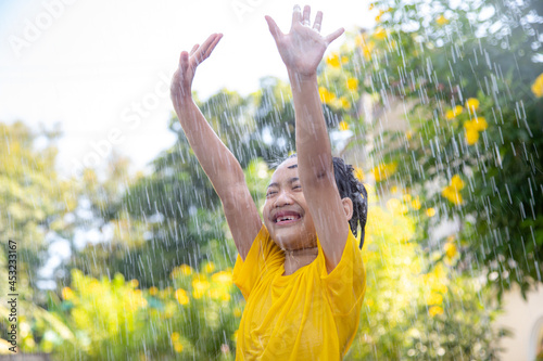 Happy Asian little child girl having fun to play with the rain in the sunlight