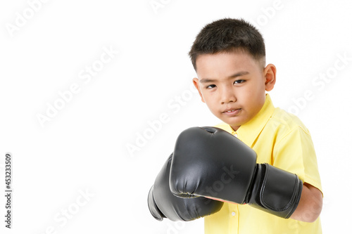 Cutout portrait of healthy Asian boy on yellow shirt wearing black boxing gloves, confidently standing and ready to fight with high intension and strong effort to win sport or game competition