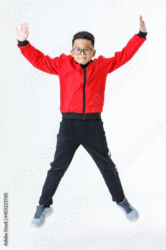 Lively cutout portrait of strong young Asian boy on red jacket and black pants happily enjoy playing of jumping up and stretching arms and legs out with smile and fun for exercise