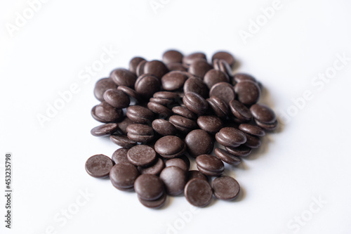 Dark chocolate chips morsels heap isolated on white background