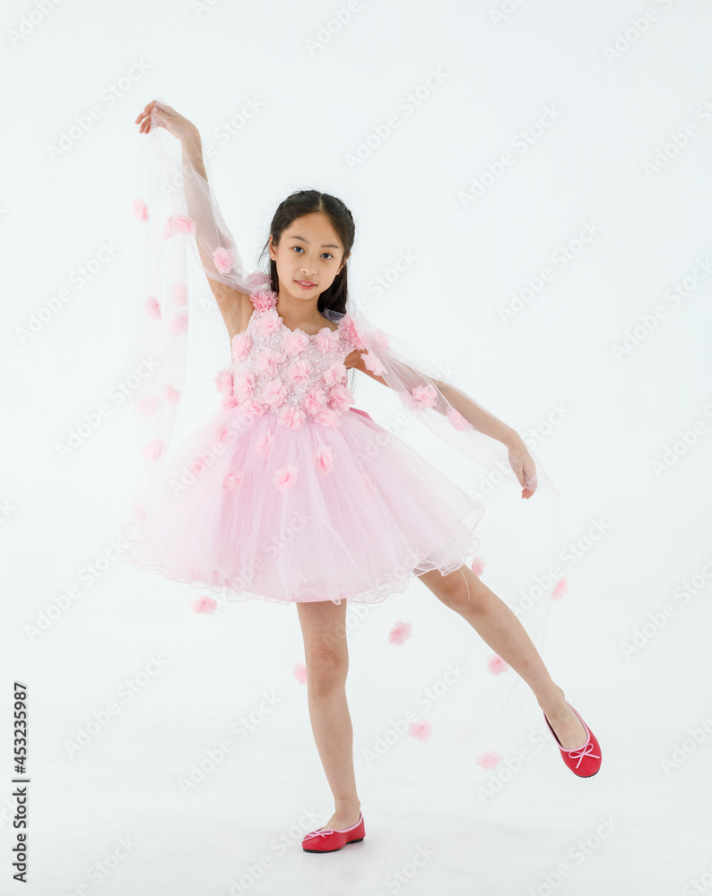 Isolated full body studio shot of little cute pretty Asian ballerina kid wears pink beautiful roses flowers ballet dress and red shoes smiling posing dancing happily in front of white background