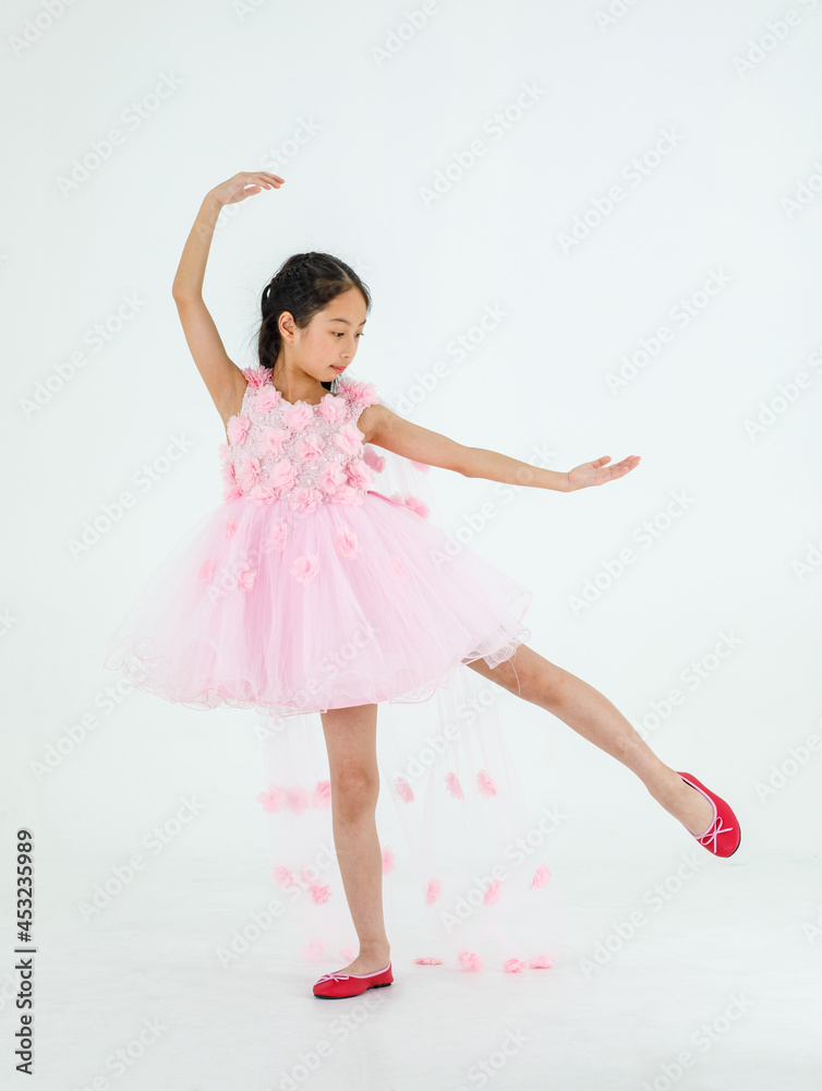 Naklejka premium Isolated full body studio shot of little cute pretty Asian ballerina kid wears pink beautiful roses flowers ballet dress and red shoes smiling posing dancing happily in front of white background
