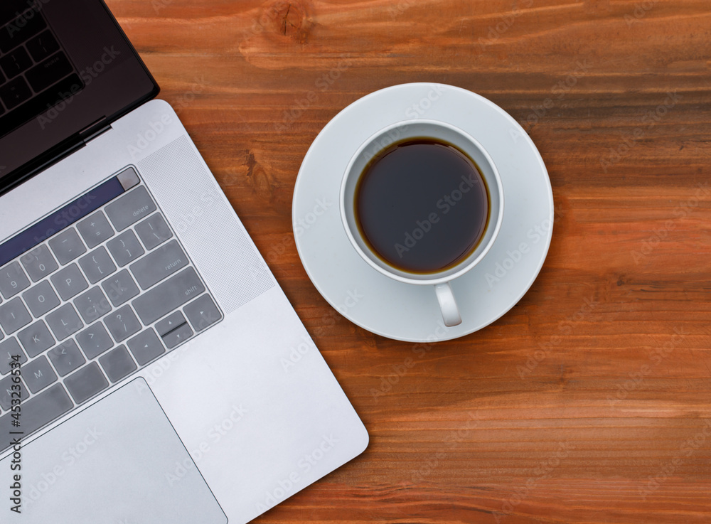 Top view shot of laptop notebook computer with black coffee in white ceramic cup on wood background with copy space Top view shot of laptop notebook computer with black coffee in white ceramic cup on wood background with copy space