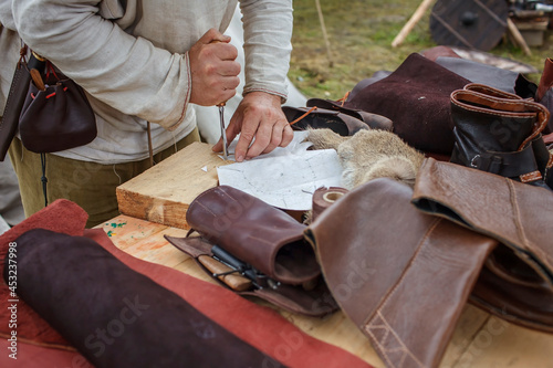 Craft shoemaker demonstrates the process and the products of his work on the festival workshop, tools and leather at cobbler workplace, diy, master of artisanal thing, middle age re-enactment