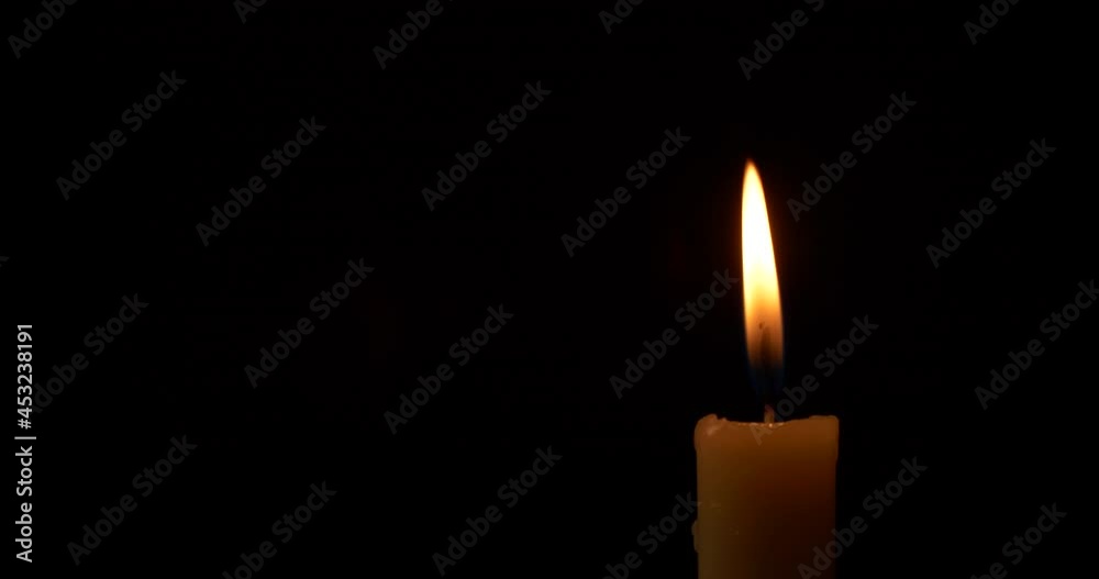 Close-up burning single candle flame isolated on black background, 4K video Close-up burning single candle flame isolated on black background, 4K video