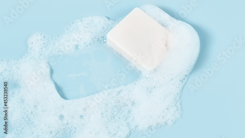 hand made soap in lush white foam on a light blue background. cosmetic background panoramic banner