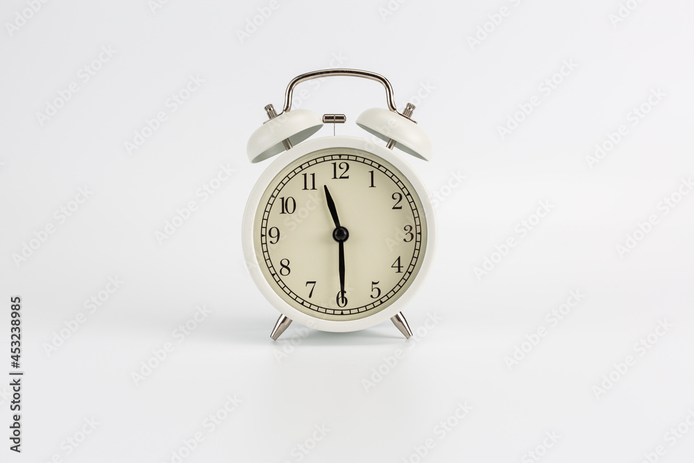 White retro clock alarm clock on white background shows 11:30 am or 11:30 pm or 23:30 White retro clock alarm clock on white background shows 11:30 am or 11:30 pm or 23:30