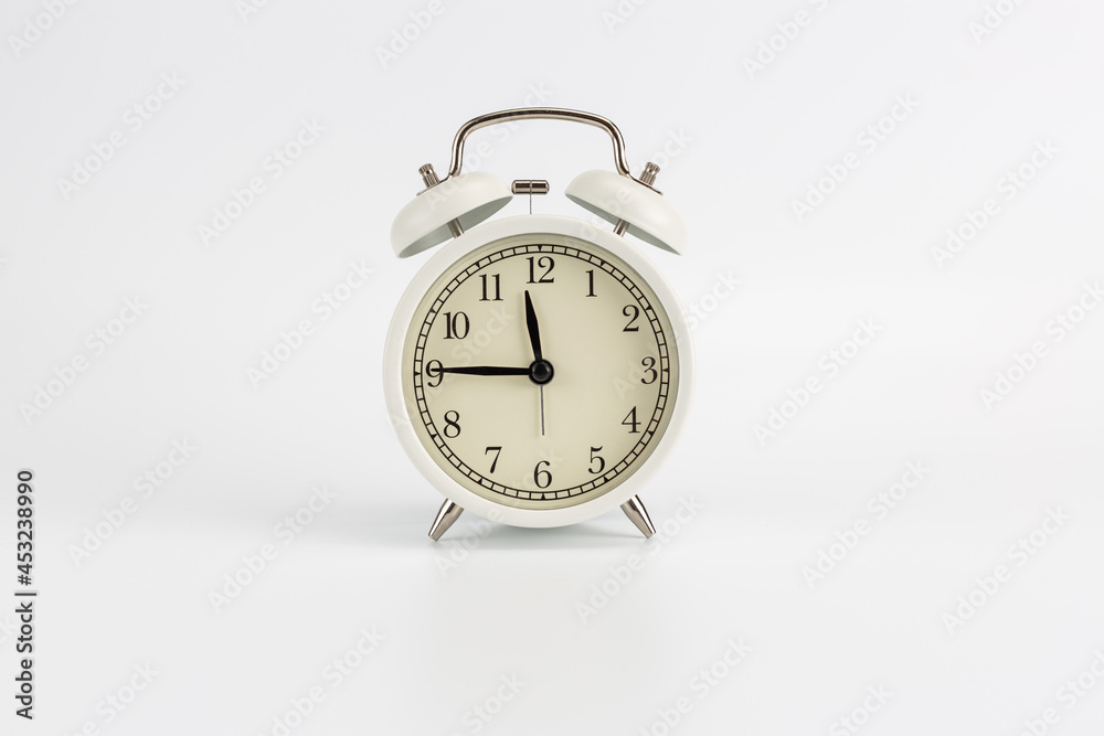 White retro clock alarm clock on white background shows 11:45 am or 11:45 pm or 23:45 White retro clock alarm clock on white background shows 11:45 am or 11:45 pm or 23:45
