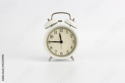 White retro clock alarm clock on white background shows 11:45 am or 11:45 pm or 23:45
