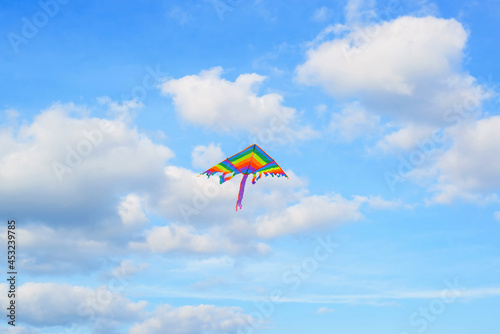 Rainbow kite flies high in blue cloudy sky. Freedom symbol, rainbow, lgbt concept