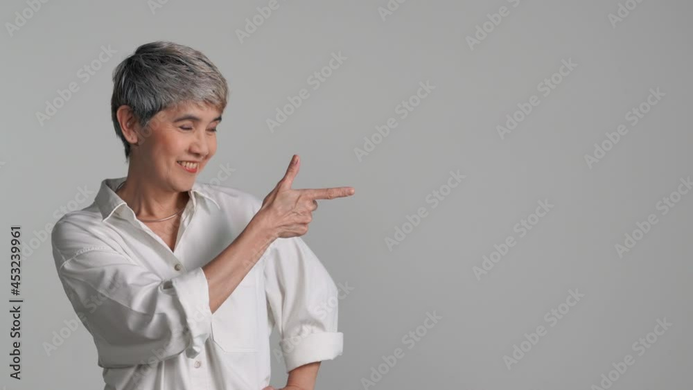 Middle aged Asian woman pointing fingers up at empty copy space for text isolated on white background Middle aged Asian woman pointing fingers up at empty copy space for text isolated on white background