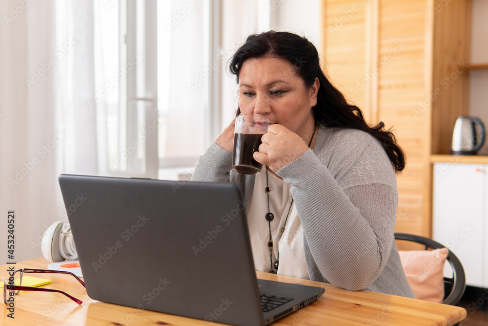 A fat woman is sitting at a table with a laptop. A fat woman is sitting at a table with a laptop.