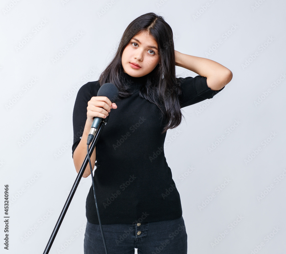 Portrait shot of an attractive smiling young Thai-Turkish teenager standing and holding the microphone while looking at the camera isolated in white background. There is copy space on side of image