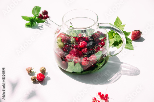 Tea with summer berries in a transparent teapot