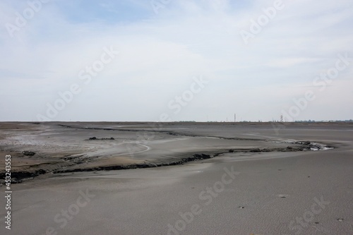 Lake of dry mud formed from a mud volcano eruption with clouds in blue sky. in Sidoarjo  East Java  Indonesia. Natural disaster in oil and gas industry and geology. No people. 