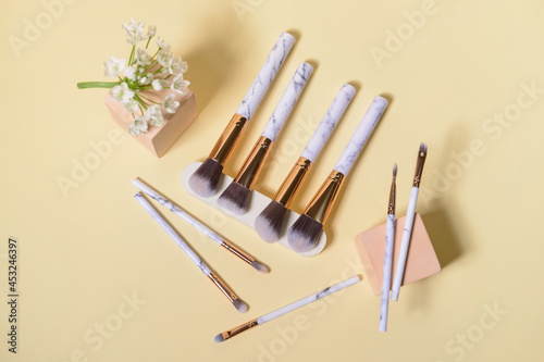 Set of makeup brushes with floral decor on color background