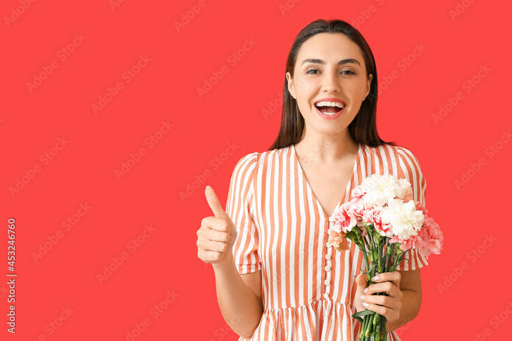 Young woman with carnation flowers showing thumb-up on color background Young woman with carnation flowers showing thumb-up on color background