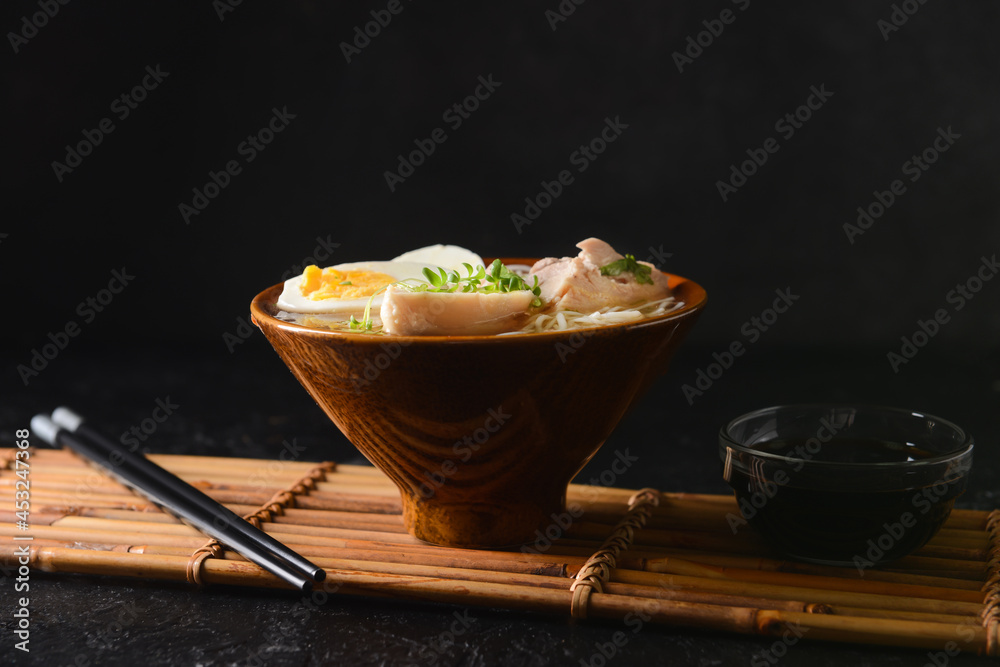 Tasty Chinese soup with chicken in bowl with soy sauce on dark background Tasty Chinese soup with chicken in bowl with soy sauce on dark background
