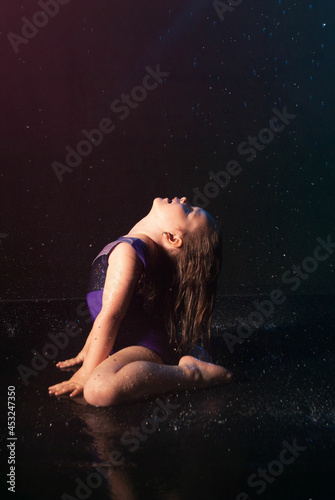 a little charming cute girl gymnast in the water on a black background in the aqua studio does sports exercises. kontsepkija sprotivnfh goods, advertising for the shopping center