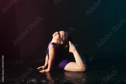 a little charming cute girl gymnast in the water on a black background in the aqua studio does sports exercises. kontsepkija sprotivnfh goods, advertising for the shopping center