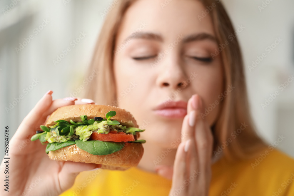 Young woman eating tasty vegan burger at home, closeup Young woman eating tasty vegan burger at home, closeup