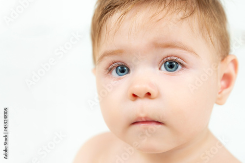 Close-up portrait of cute baby boy with beautiful blue eyes and long eyelashes over white background. Pretty boy. Copy space.