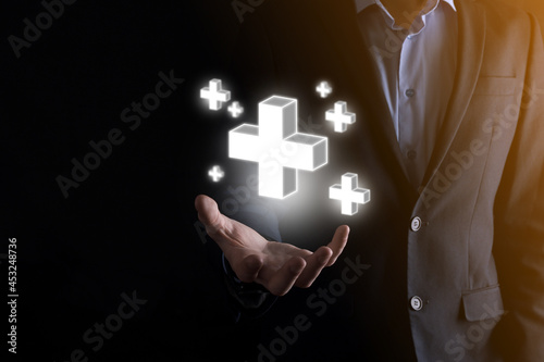 Businessman hold 3D plus icon, man hold in hand offer positive thing such as profit, benefits, development, CSR represented by plus sign.The hand shows the plus sign