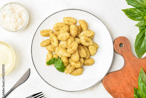 Composition with tasty pesto gnocchi on light background