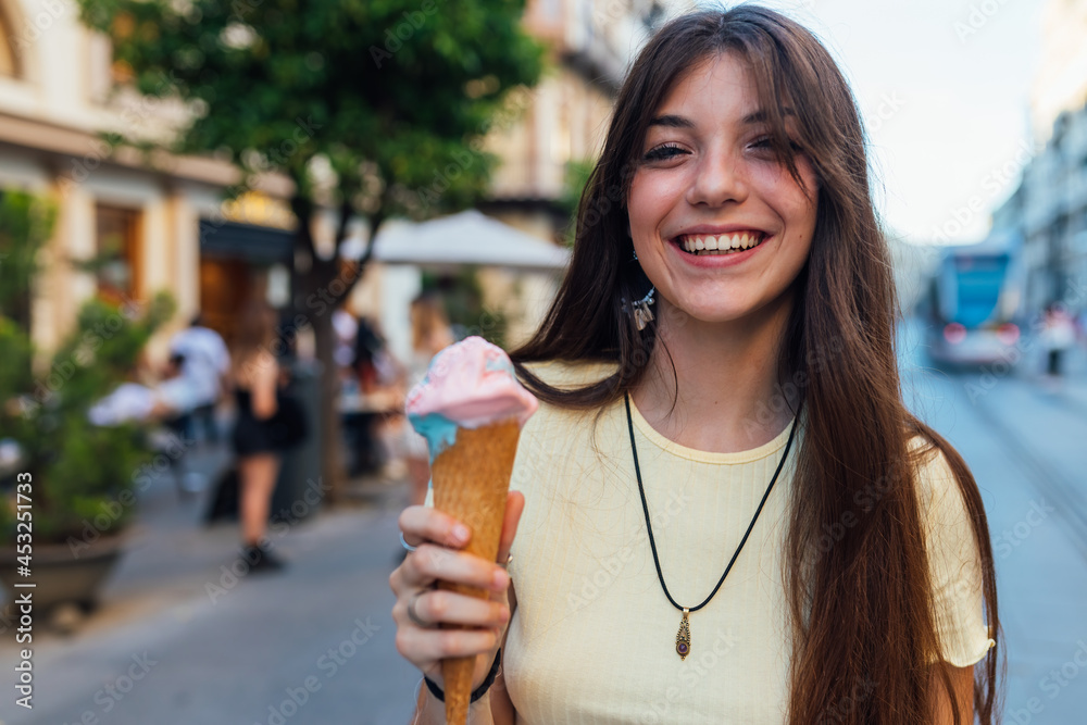 Crop happy woman with tasty ice cream cone in town Crop happy woman with tasty ice cream cone in town