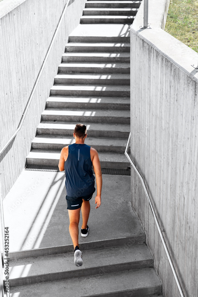 fitness, sport and healthy lifestyle concept - young man running upstairs