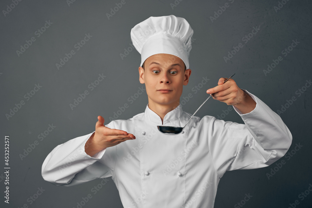 a man in a chef's uniform with a ladle in his hands cooking food kitchen professional a man in a chef's uniform with a ladle in his hands cooking food kitchen professional