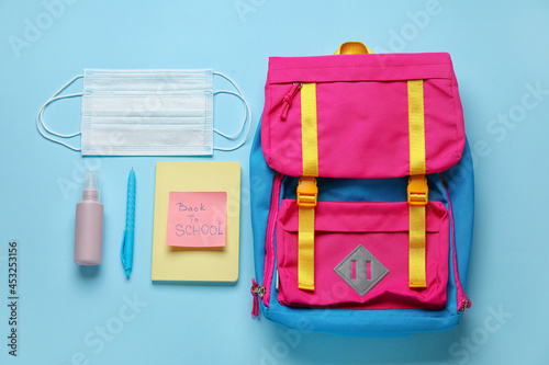 Paper with text BACK TO SCHOOL, backpack and stationery on color background