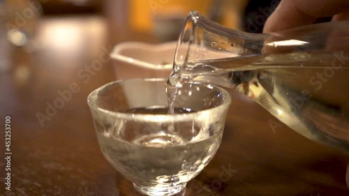 SLOWMO close up of man's hand pouring sake into a cup