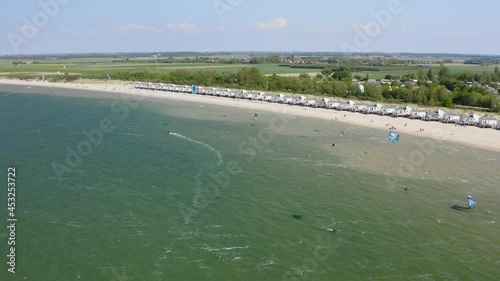 Aerial orbit over the beach near Wissenkerke, the Netherlands on a windy day with many kitesurfers riding on the wind photo