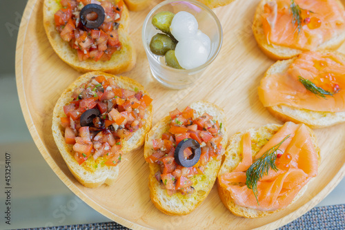 Top view and selective focus of tapas which is small portion appetizer food (smoked salmon, cooked tomato and parma ham on toasted breads) served in european restaurant for sharing before meal.