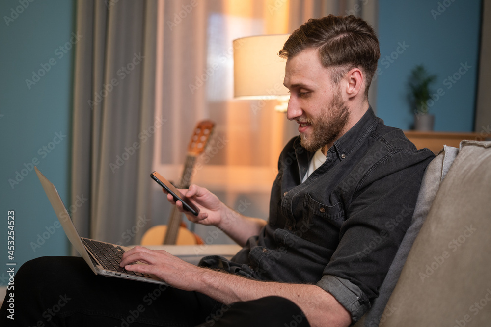Portrait of businessman working on computer at home on couch, holds laptop on lap, answers email, sends messages, posts to website, makes phone calls to clients, dials phone number from ad Portrait of businessman working on computer at home on couch, holds laptop on lap, answers email, sends messages, posts to website, makes phone calls to clients, dials phone number from ad