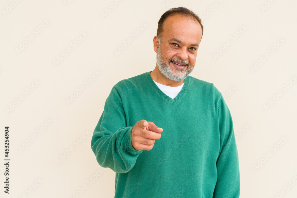 Portrait of happy bearded Indian man smiling against plain wall Portrait of happy bearded Indian man smiling against plain wall